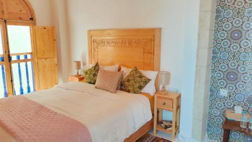 a bedroom with a bed with a wooden headboard at Riad Al Manara in Essaouira