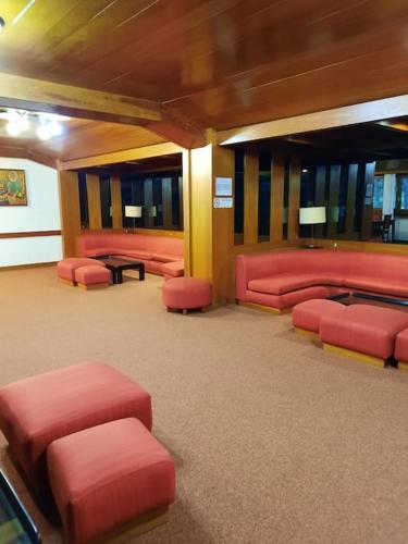 a waiting room with red chairs and tables at Casa StePa in Pescasseroli