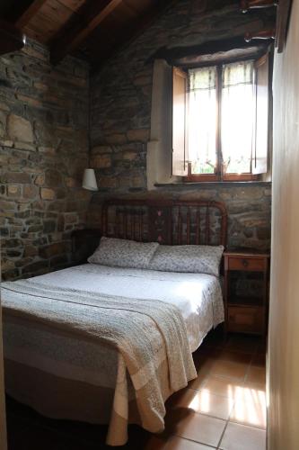 a bedroom with a bed and a stone wall at Casa Chidro in Buesa