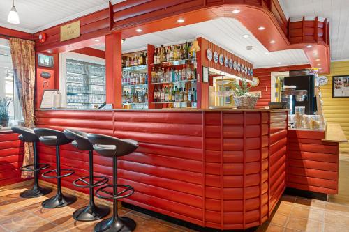 a red bar with stools in a restaurant at Lyngseidet Gjestegård AS in Lyngseidet