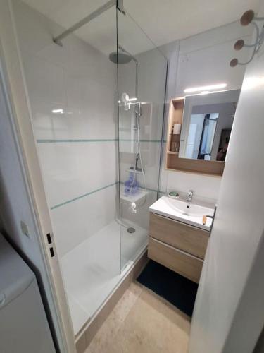 une salle de bain blanche avec une douche et un lavabo dans l'établissement Appartement cosy en résidence privée, bord de mer, à Six-Fours-les-Plages
