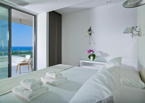 a white bedroom with a bed with towels on it at Youphoria Sea View Villas in Kissamos