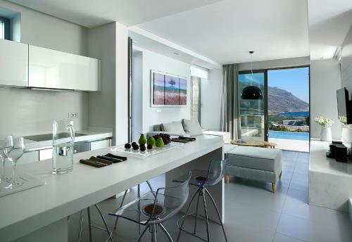 a white kitchen with a counter and a living room at Youphoria Sea View Villas in Kissamos