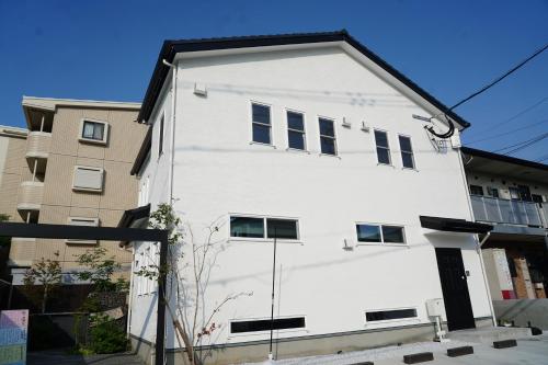 a white building with a black roof at 泊まる寿司屋一力 Sushi house in Itoshima