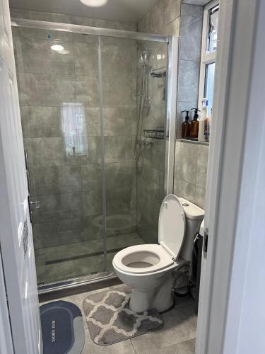 a bathroom with a shower with a toilet and a glass shower stall at Garden Guest House in Enfield Lock