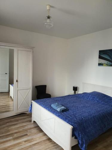 - une chambre blanche avec un lit et une couverture bleue dans l'établissement Sojeaflor, à Coutras
