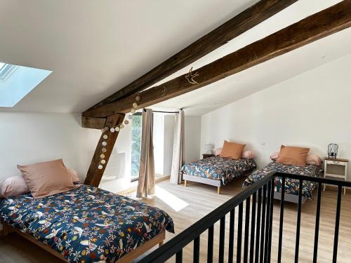 Cette chambre mansardée comprend deux lits et un balcon. dans l'établissement Gîte du Chat Roux, à La Chapelle-Saint-Martin-en-Plaine