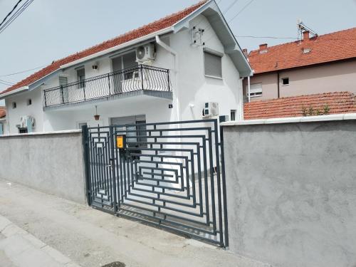 a white house with a gate with stairs on it at Gostinska kuća in Leskovac