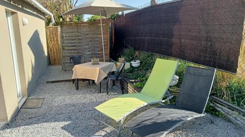 un patio avec une table, des chaises et un parasol dans l'établissement Logement T2 avec terrasse idéal Loire à vélo, à Saint-Brévin-les-Pins