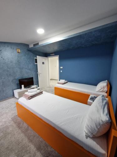 a bedroom with two beds and a blue wall at Apartmani Maksa in Stanovo