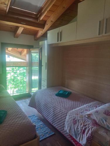 a bedroom with two beds and a large window at Appartamento Orchidea Garda in Garda
