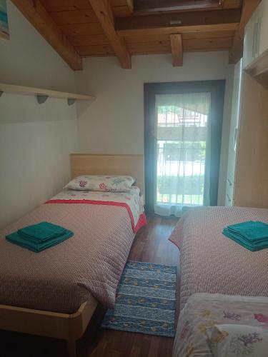 two beds in a room with a window at Appartamento Orchidea Garda in Garda