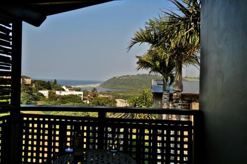 a balcony with a view of the ocean and a palm tree at Villa La Mercy Chalet No load shedding or water outages in La Mercy