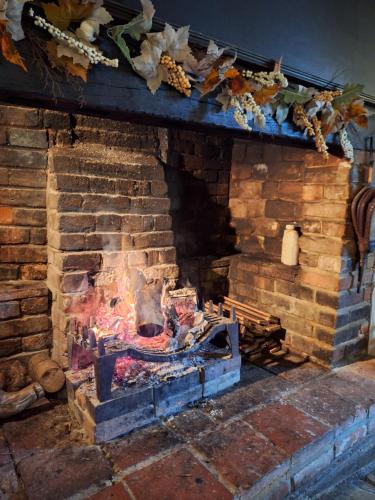 a brick fireplace with a fire inside of it at George & Dragon Country Pub & Hotel Wolverton Townsend in Tadley