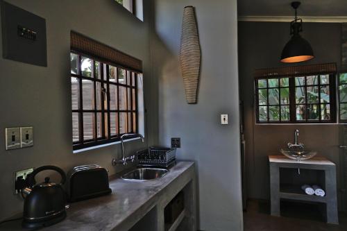 een keuken met een wastafel en 2 ramen bij Villa La Mercy Chalet No load shedding or water outages in La Mercy