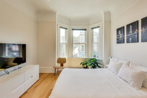 um quarto branco com uma cama branca e uma televisão em 4br2ba Remodeled Home In The Heart Of The Castro! em São Francisco