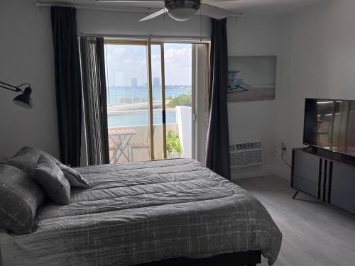 a bedroom with a bed and a television and a balcony at Unique Water Views, free Parking 1bed 1 bath Rooffornomads 416 in Miami Beach