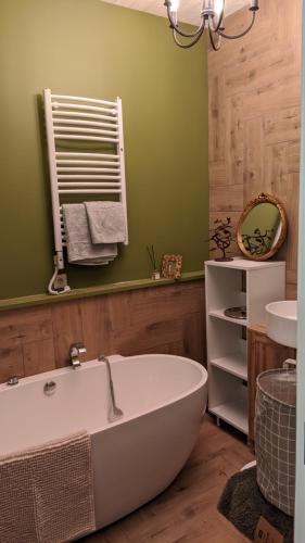 a bath tub in a bathroom with a green wall at Svečių namelis KNYGŲ NAMAS in Kelmė