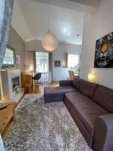 a living room with a brown leather couch and a living room with a television at Safari Cottage, Kidderminster in Kidderminster
