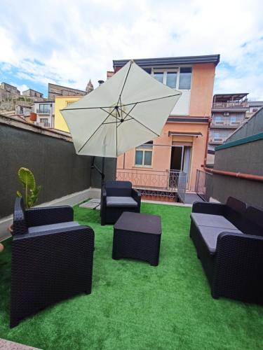 a patio with chairs and an umbrella on the grass at Via San Vincenzo, 21 in Castiglione di Sicilia