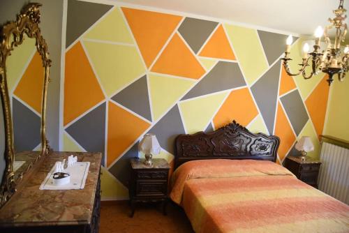 Un dormitorio con una pared colorida con una cama y un espejo. en Cascina Speronetti, en Canale