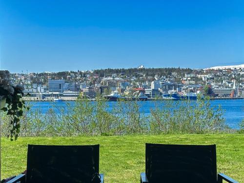 two chairs sitting in a field next to a body of water at Panorama View - FREE Parking - PERFECT For Couples in Tromsø