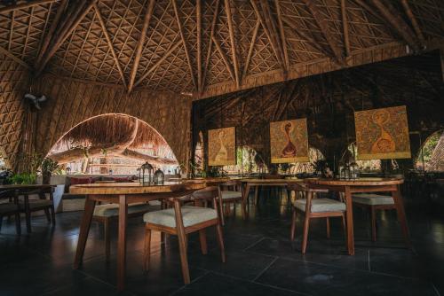a restaurant with wooden tables and chairs and a ceiling at Kokoro Mio Hotel & Wellnes in Xul-Ha