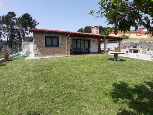 a small stone house with a grass yard at Casa con vistas al mar in Noya