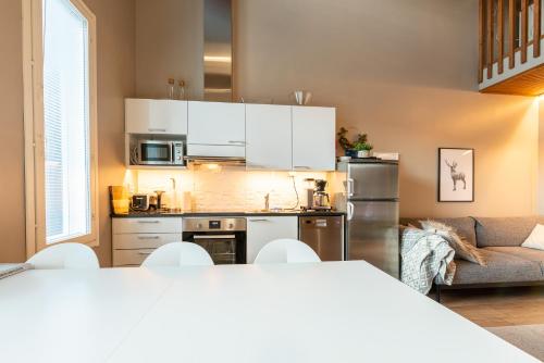 a small kitchen with white cabinets and a couch at Aurinkorinne 2 - Modern 2BD & Loft, free wifi & sauna in Syöte