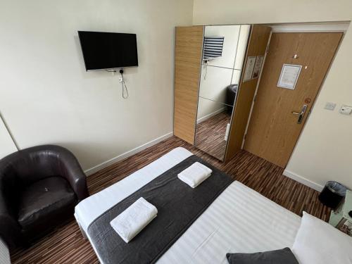 a bedroom with a bed and a chair and a television at Namaste Palace Hotel in Norwich