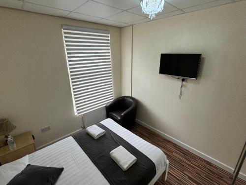 a room with a bed and a chair and a television at Namaste Palace Hotel in Norwich