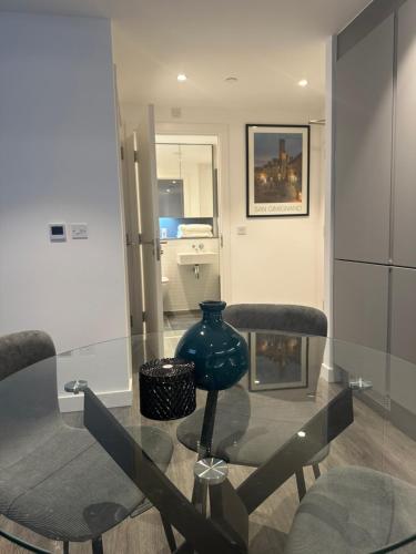 a glass table with two chairs and a vase on it at HE Luxury in Abbey Wood