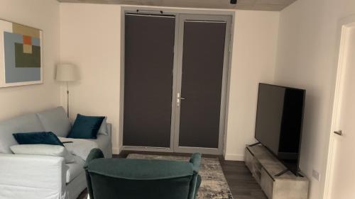 a living room with a white couch and a television at HE Luxury in Abbey Wood