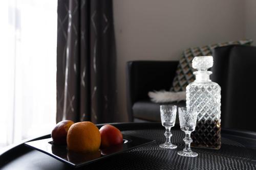 a plate of fruit on a table with a bottle and glasses at Apartmán NAVRCHU in Brezno