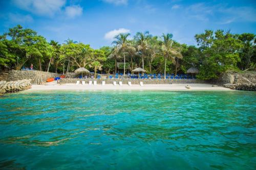 uma praia com cadeiras e guarda-sóis na água em Hotel San Pedro de Majagua em Isla Grande