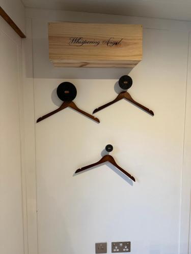 a wall with three wooden hangers on it at Apple-tree lodge in Taunton