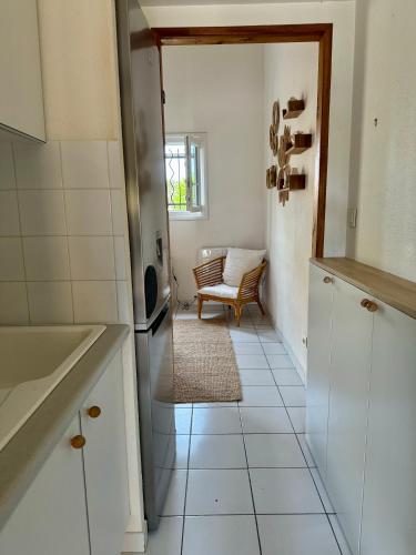 une cuisine avec un sol carrelé blanc et une chaise dans l'établissement La plage à 2min à pied, 2 extérieurs,wifi,Clim, au Barcarès