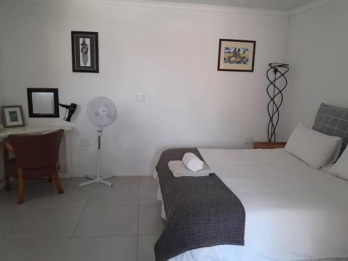 a bedroom with a bed and a desk with a fan at Cottage @19th in Pretoria