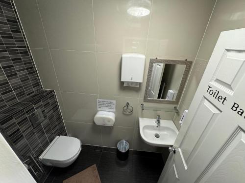 a small bathroom with a toilet and a sink at Namaste Palace Hotel in Norwich
