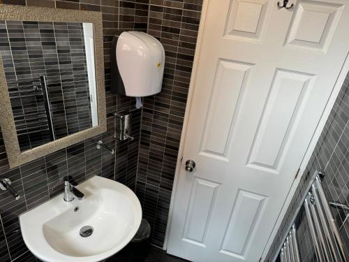 a bathroom with a sink and a white door at Namaste Palace Hotel in Norwich