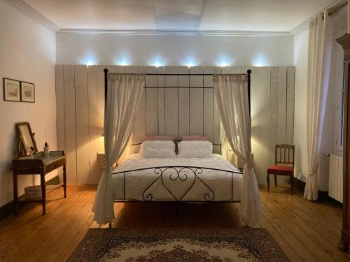 a bedroom with a bed with a canopy at Les Croque-Notes, chambres et table d'hôtes in Lorignac