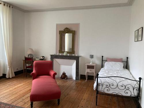 a bedroom with a bed and a chair and a mirror at Les Croque-Notes, chambres et table d'hôtes in Lorignac