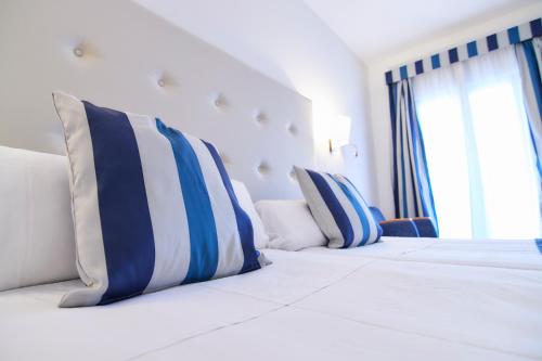 a bedroom with two beds with blue and white pillows at Los Geranios in Port de Soller