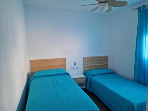 two beds in a small room with blue sheets at Casas Miramar in Tarifa