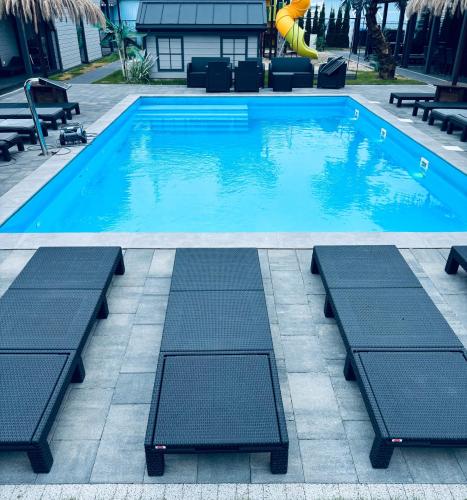 a swimming pool with two chaise lounges in front at Wierzbowa Dolina Mielno in Mielno