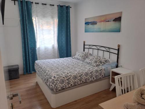 een slaapkamer met een bed en een raam met blauwe gordijnen bij Aeropuerto Barcelona -Mi colibrí in El Prat de Llobregat