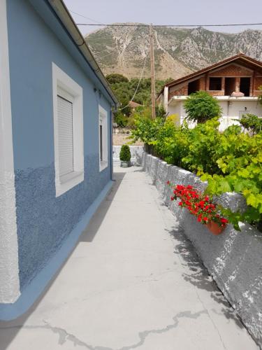 a sidewalk next to a blue building with flowers at villa Narkissos - Καναλάκι - Εξοχική κατοικία in Nárkissos
