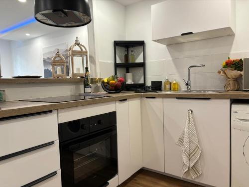 a kitchen with white cabinets and a black dishwasher at Rhein Stopover - Appartement 2 Personnes in Huningue