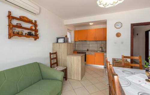 a kitchen and dining room with a green couch and a table at Stunning Apartment In Omisalj With Wifi in Omišalj