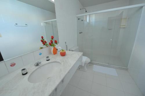 a white bathroom with a sink and a shower at Rede Andrade Plaza Salvador in Salvador